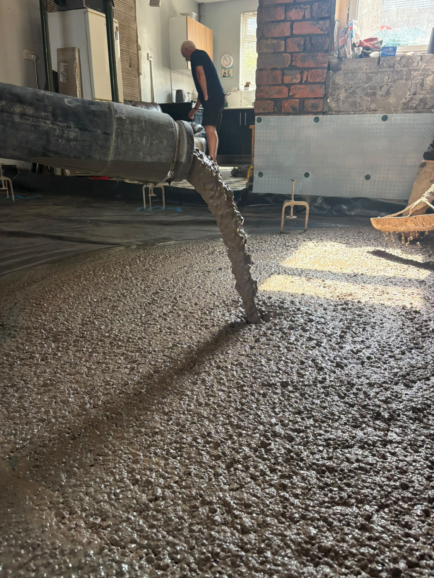 Pump hose placing concrete into a ground floor slab