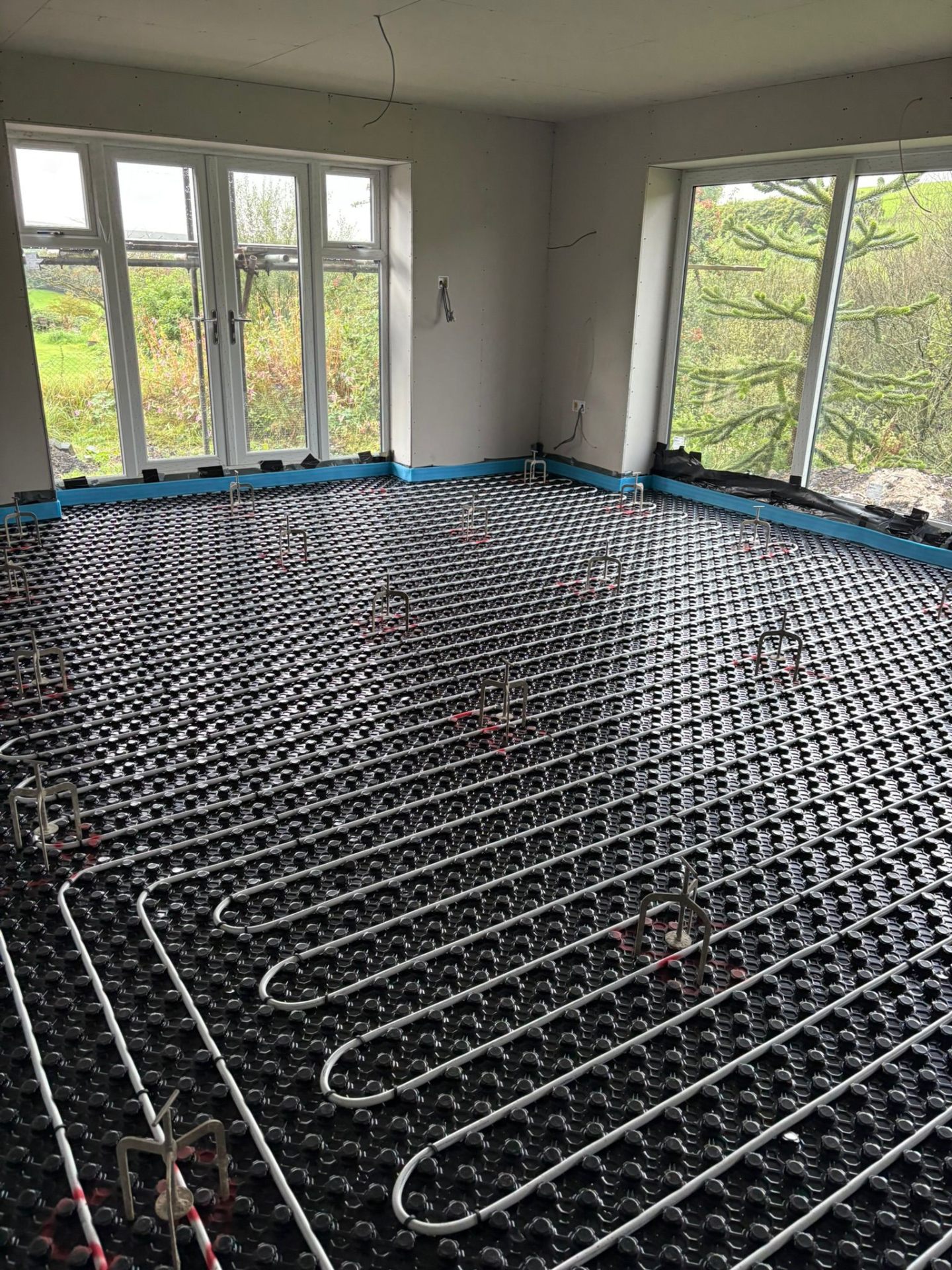 UFH pipework in a garden-room with full-height glazing